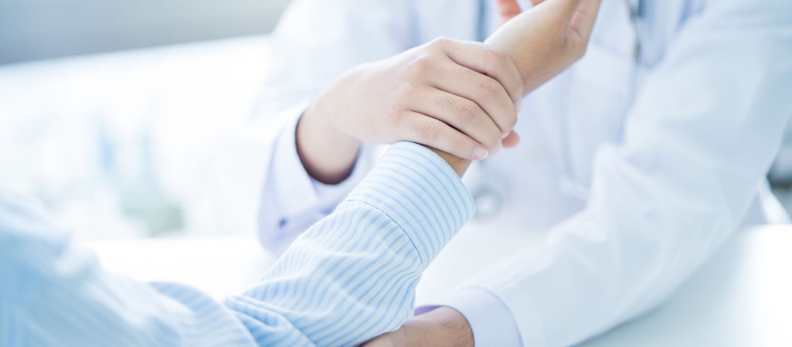 Orthopedist examining injured arm of male patient